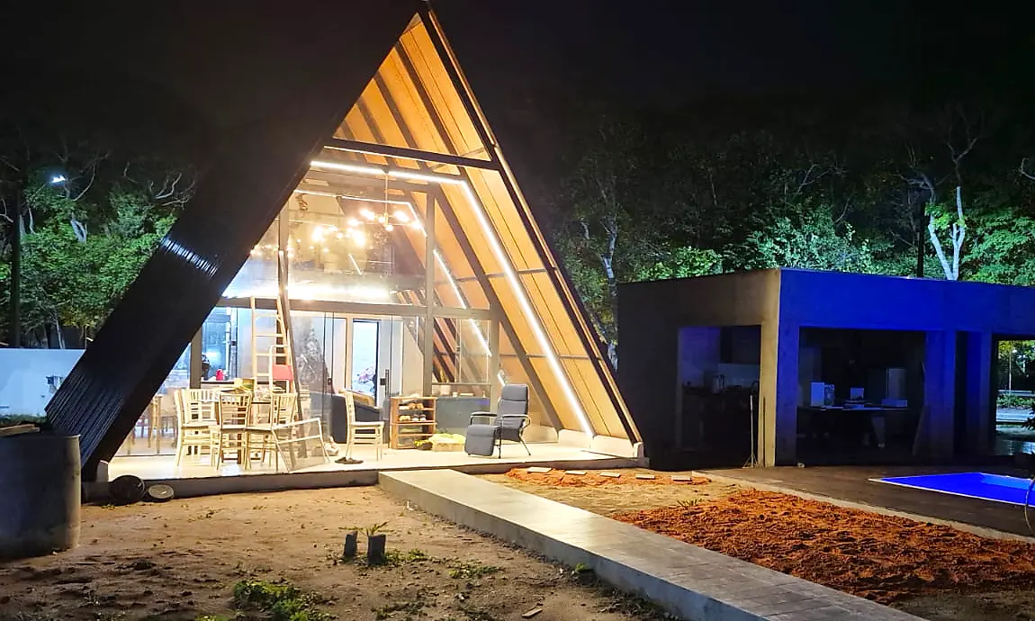 Chalé A-frame iluminado à noite, coberto com telha Ecorenovar